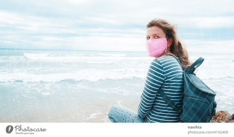 Young woman wearing a pink face mask sitting near the sea hope brave strong covid coronavirus beach ocecan free freedom survivor hopeful dream health medical