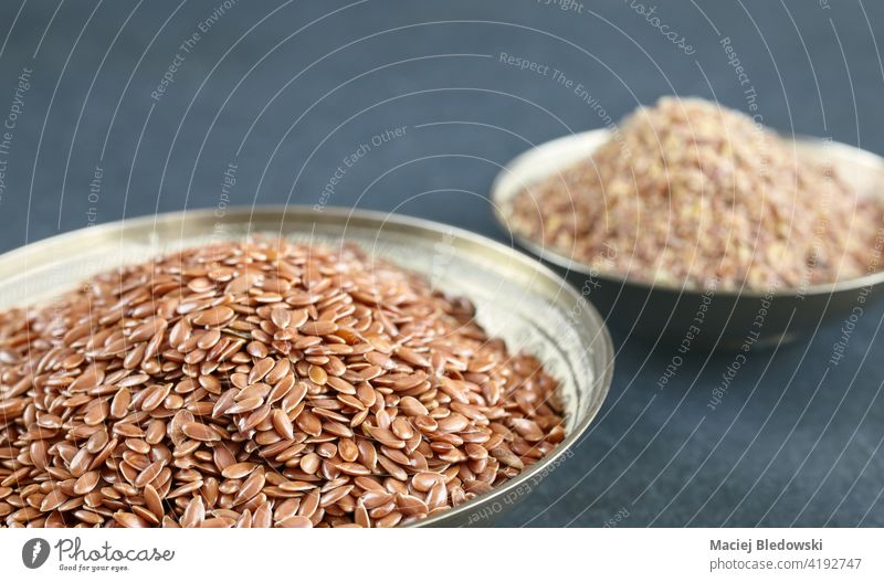 Flaxseed in a bowl with blurred ground linseed in background, selective focus. flaxseed natural healthy raw ingredient grain organic vegan nutrition food diet