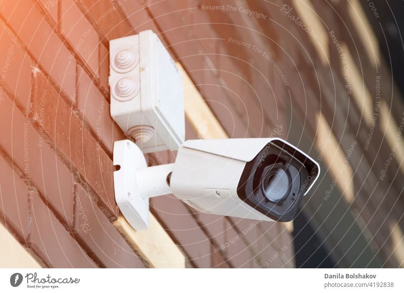 Closed-circuit television camera mounted on brick wall. CCTV security camera outdoors. supervision warning prevention detection inspect detector police secrecy