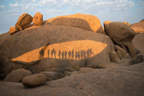 Rocks at Damaraland with the shadows of a group of people on a sunny day Namibia enjoy happy together desert hot sky friends rocks orange sunset holidays