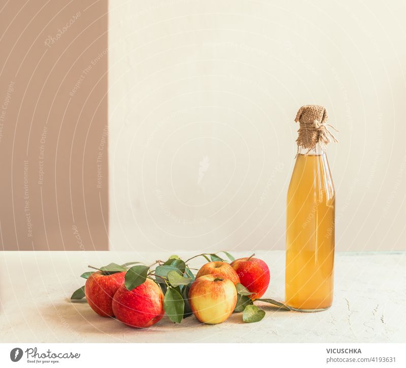 Bottle of homemade apple vinegar with fresh apples and green leaves on white kitchen table. Still life juice bottle still life ingredient raw vitamin beverage