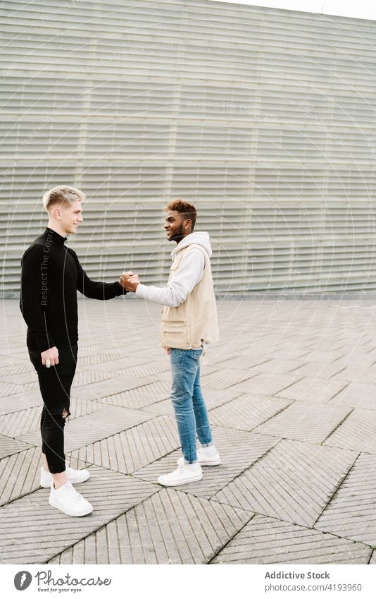 Trendy multiethnic men giving dap after meeting on street handshake greeting trendy friend together city style relationship positive friendship young diverse