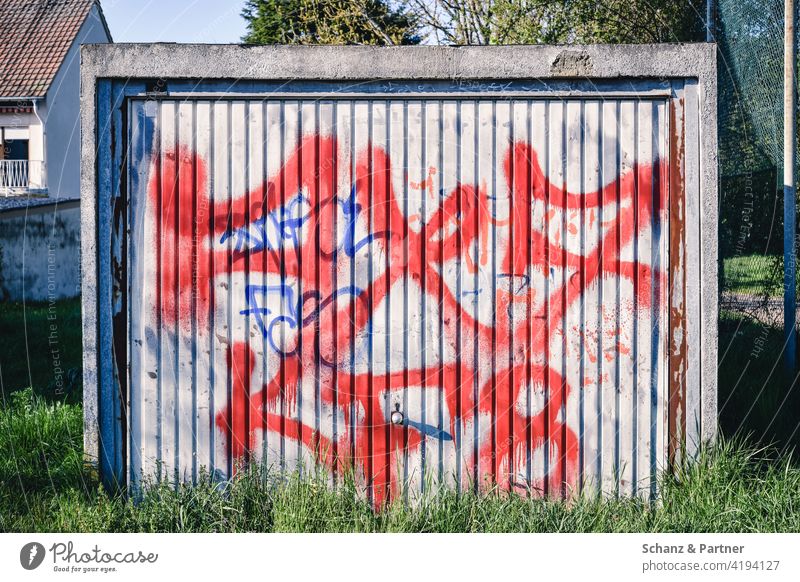 Graffiti sprayed garage door of a prefabricated garage Garage door Entrance Red Prefabricated garage overgrown Concrete Tags Tin Forget Weathered mystery Goal