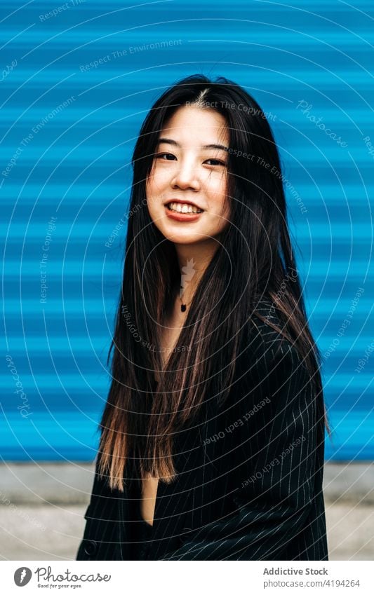 Long hair brunette asian woman looking at camera with a blue background japanese young female model chinese style attractive lady street modern stylish portrait