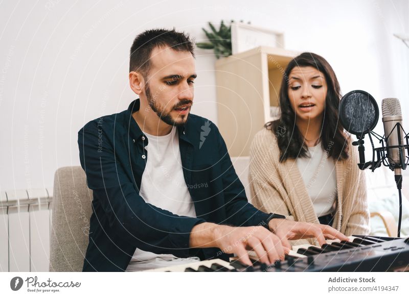 Couple recording song at home couple sing play synthesizer music musician together singer microphone sound audio rehearsal melody rhythm instrument perform