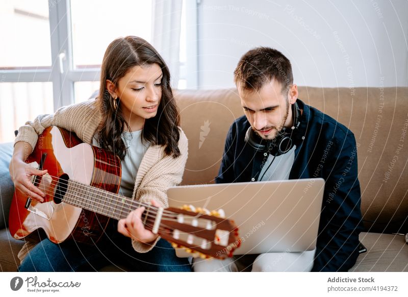 Couple recording song at home couple music musician guitar play laptop acoustic sofa gadget guitarist melody using hobby sound sit device together relationship