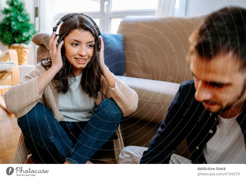 Content woman listening to music in headphones couple compose song together create home musician floor sound melody sit using creative talent skill audio tune
