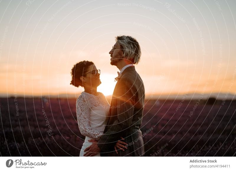 Newlyweds standing close on field at dusk couple newlywed sunset romantic nature valentine face to face occasion affection relationship love peaceful