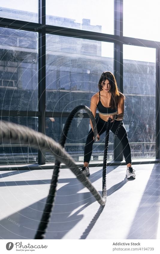 Active woman exercising with battle ropes in gym sportswoman athlete training endurance effort strong power intense workout exercise wellbeing motivation energy