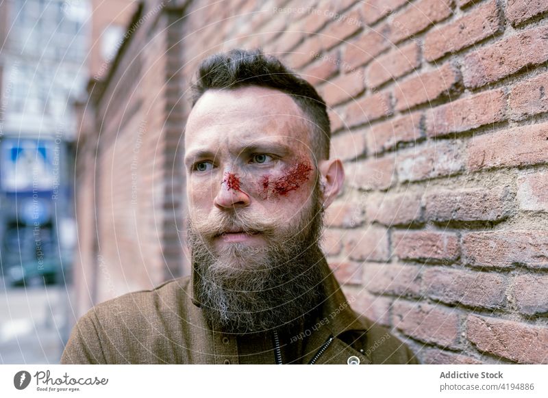 Side view hipster man with beard and cinema makeup posing on the street movie makeup actor film hispter bearded face model shooting studio wound costume