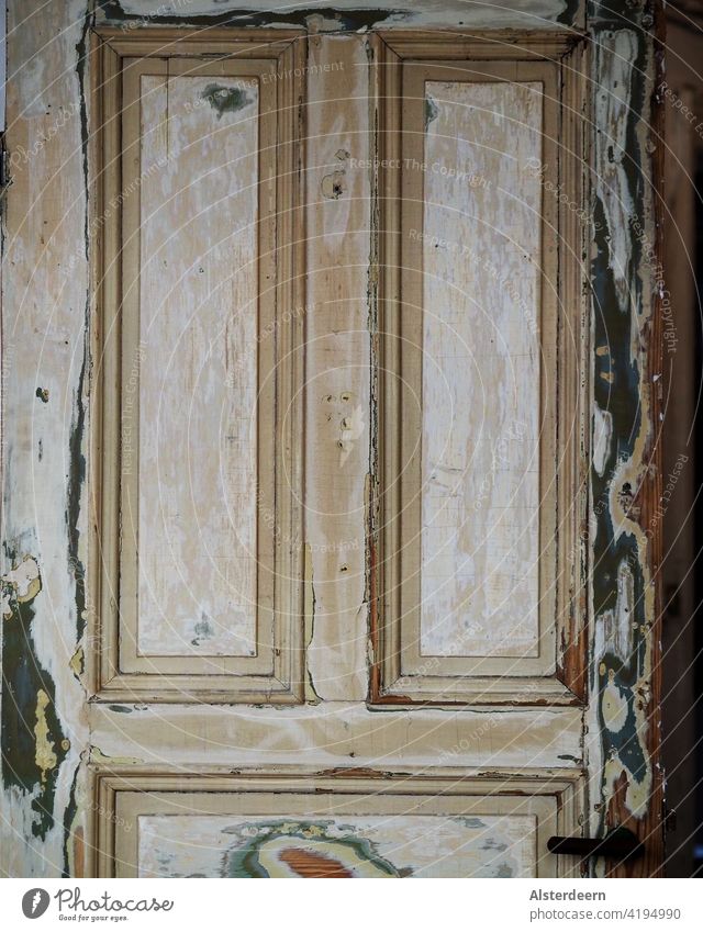 Upper half of an old door in an old flat that has many layers of paint, has been sanded down but not yet repainted the door handle can be seen Wooden door