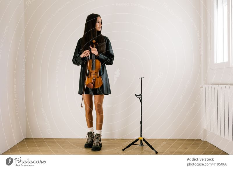 Musician standing with violin in empty room woman musician hobby acoustic leisure instrument classic art string female think tranquil concentrate professional