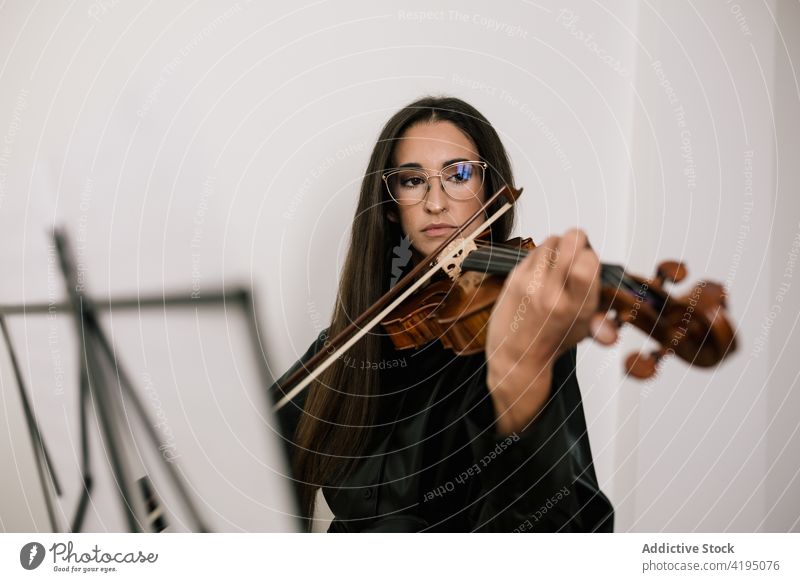 Musician playing violin during rehearsal in studio woman artist instrument serious melody skill instrumental classic female practice violinist player focus