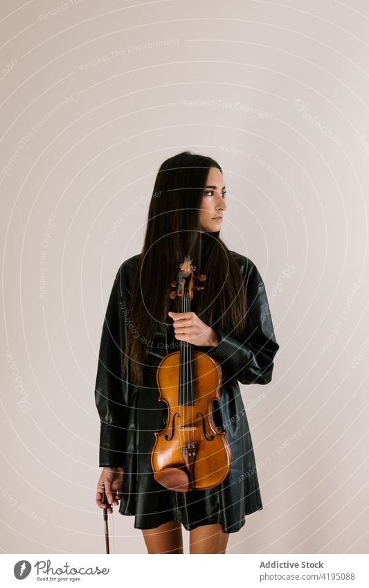 Musician standing with violin in empty room woman musician hobby acoustic leisure instrument classic art string female think tranquil concentrate professional
