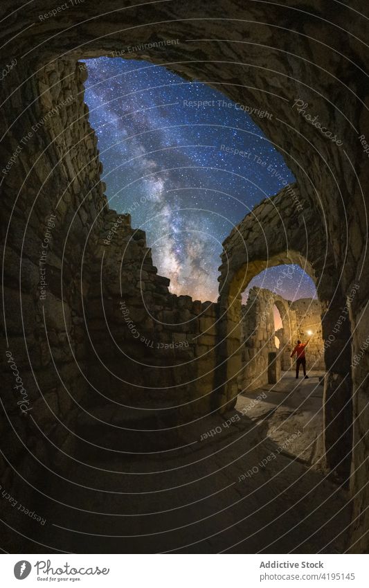 Faceless traveler hiking ruins of castle at night tourist explore ruined lantern sightseeing milky way starry remain old ancient abandoned architecture medieval