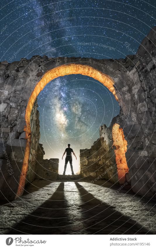 Tourist standing under arched passage of ancient ruins traveler silhouette starry admire night church heritage milky way astronomy old tourism building explore