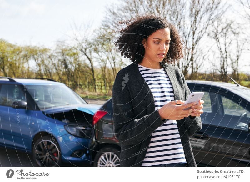 Female Driver Contacting Car Insurance Company On Mobile Phone After Road Traffic Accident woman driver car accident wreck crash insurance claim calling