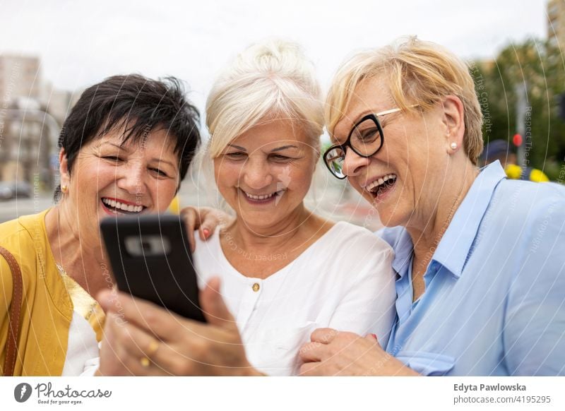 Group of senior women using smartphones together woman people retired retirement grandmother leisure standing confident attractive urban city street beautiful