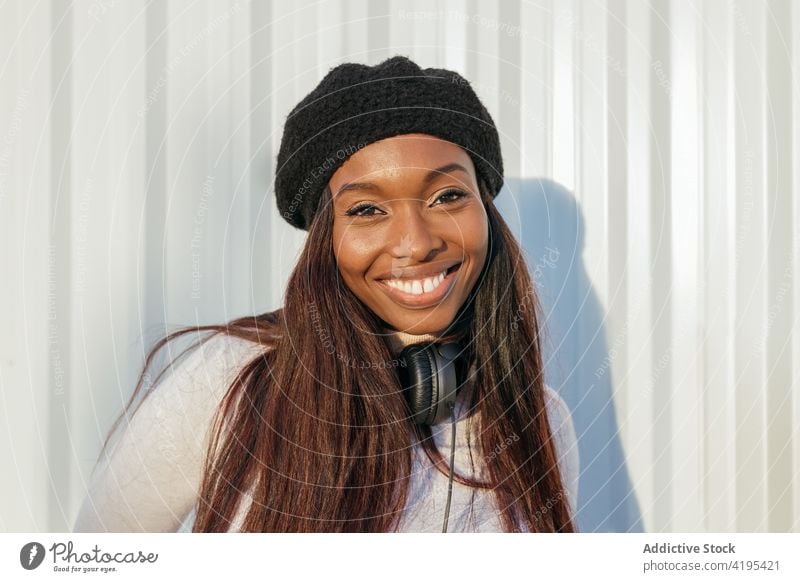 Charming black woman looking at camera in city charming appearance smile beret headphones cheerful beauty natural female ethnic african american happy building
