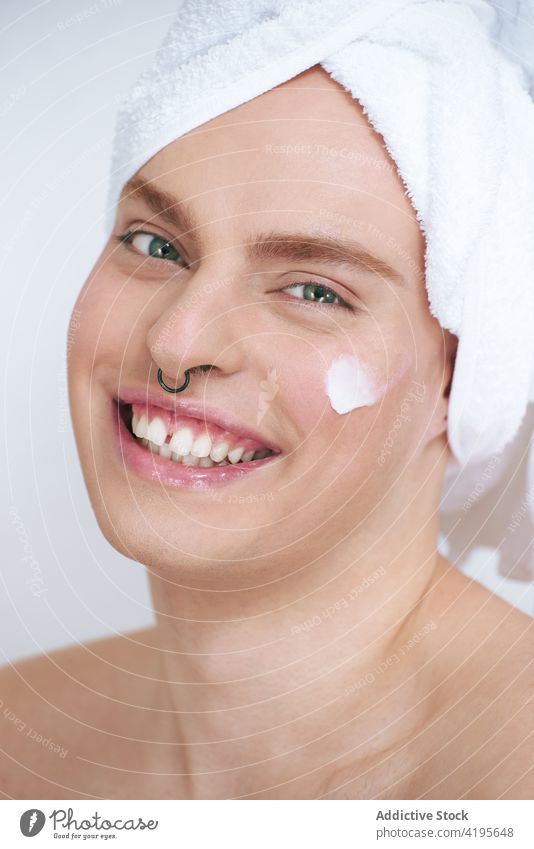 Transgender man applying moisturizing cream on cheeks gay beauty skin care facial feminine portrait nourishing product transgender cosmetic manicure piercing