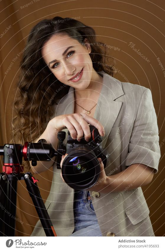 Positive young lady taking pictures on professional camera during photo session in studio woman take photo photo camera happy smile photographer photo shoot