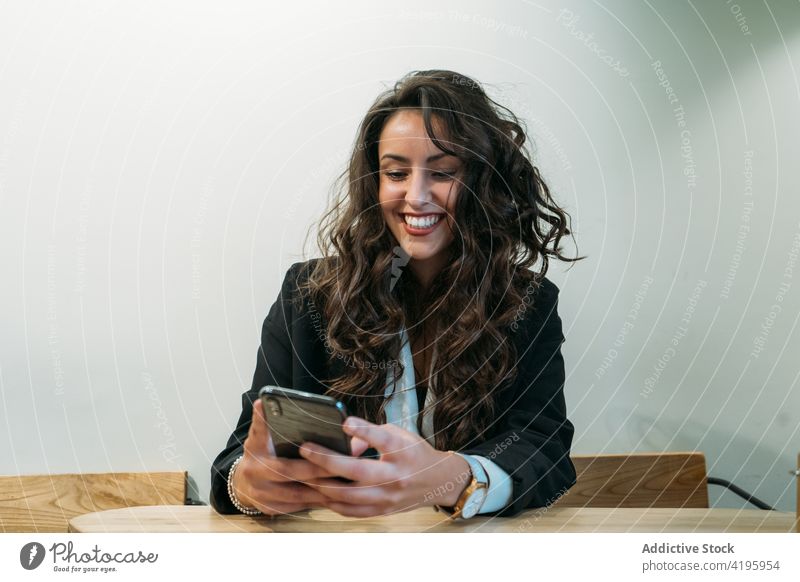 Smiling businesswoman using smartphone in cafe work browsing entrepreneur smile wait order style female table suit job connection surfing cheerful remote online