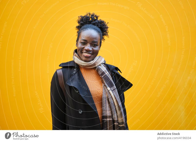 Cheerful black woman in trendy wear on yellow background sincere toothy smile friendly pleasant style ornament feminine bright portrait street african american