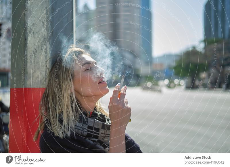 Woman smoking cigarette near city road in sunlight woman smoke puff exhale vapor cloud enjoy town post steam individuality cool roadway feminine tobacco haze