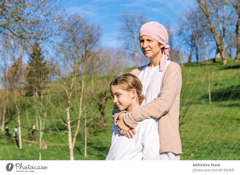 Sick mother embracing daughter in park woman together cancer love thoughtful relationship summer embrace disease parent relax concept pink girl family child