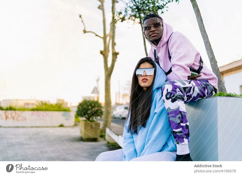 Stylish multiracial friends resting on pavement in city partner fashion style individuality cool sunglasses creative design town portrait spend time woman