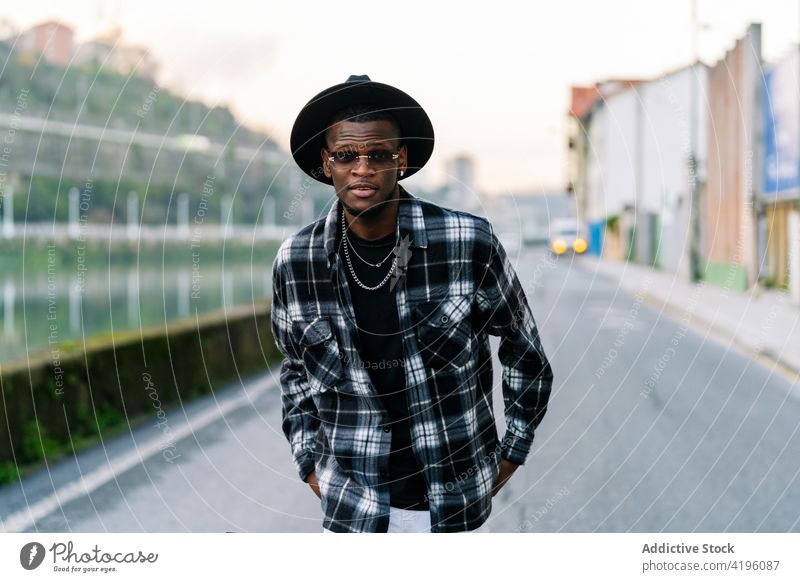 Stylish black man in hat on city road fashion style individuality cool masculine macho town african american ethnic jeans checkered shirt contemporary