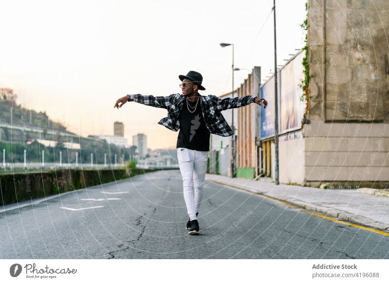 Stylish black man in hat on city road fashion style individuality cool outstretch masculine macho town african american ethnic jeans checkered shirt