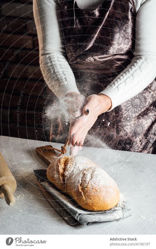 Crop baker sprinkling loaf of bread with flour in bakery artisan sprinkle dust baked culinary recipe woman tasty natural craftswoman fresh yummy table golden