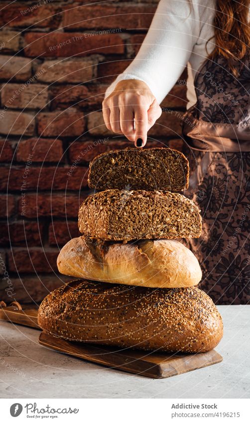Crop artisan showing cut multigrain bread in bakehouse baker cereal nutrient protein fresh crunchy delicious woman bakery soft yummy table baked tasty sunflower