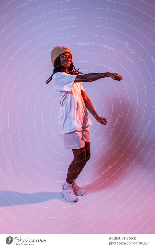 Black teenage girl dancing freestyle in studio dancer hobby cool hip hop move motion energy neon light dynamic studio shot generation perform urban active braid
