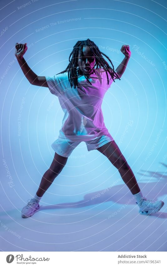 Black teen dancer in headphones in studio girl teenage light posture illuminate youngster neon cool glow generation urban bright modern confident style black