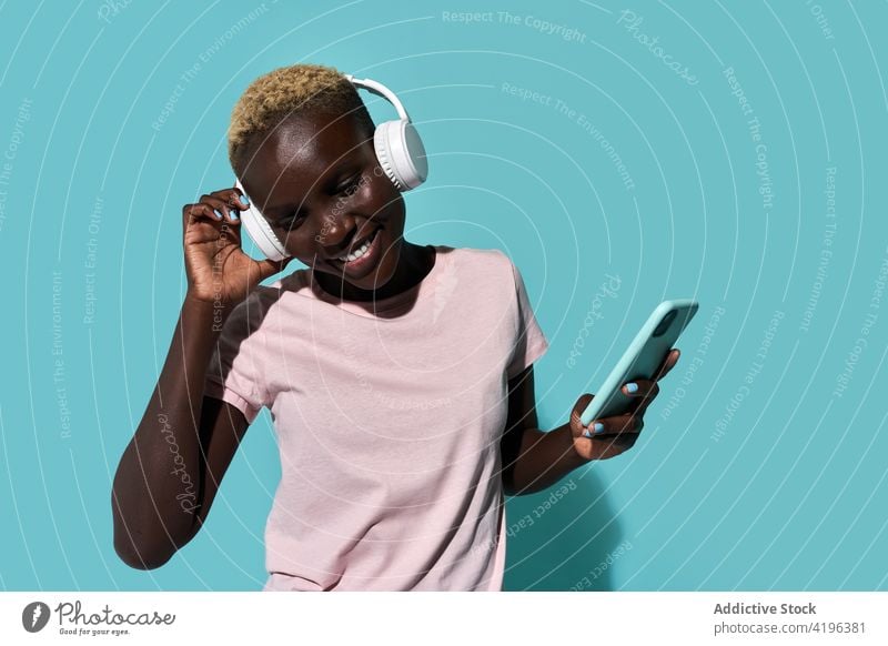 Excited black woman with headphones and smartphone music dance african charismatic expressive audio device song gadget female glad american mobile phone tune