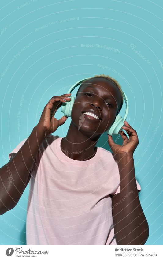 Excited black woman with headphones music african charismatic expressive audio device song gadget female glad american tune short hair listen happy attractive