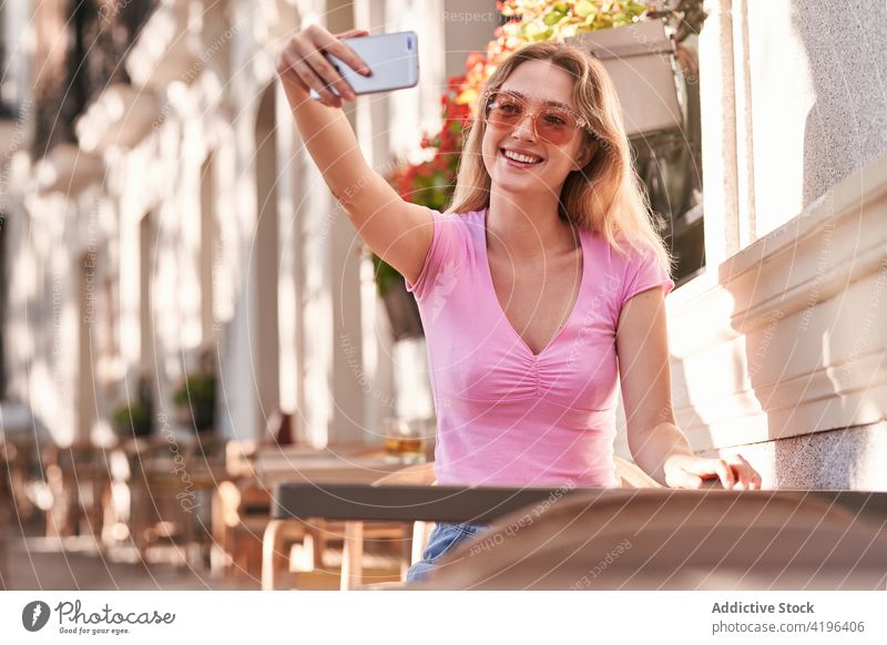 Smiling teen female taking selfie on smartphone sitting on street woman teenage using surfing texting connection positive watch scroll wireless internet