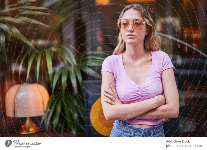 Serious teen woman with hands crossed against glass wall concern serious teenage worried think problem concentrate gaze uncertain female thoughtful ponder
