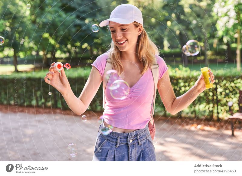 Teen woman blowing soap bubbles in park teen carefree pastime glad fun enjoy female smile optimist adolescent nature summer teenage playful sunlight madrid