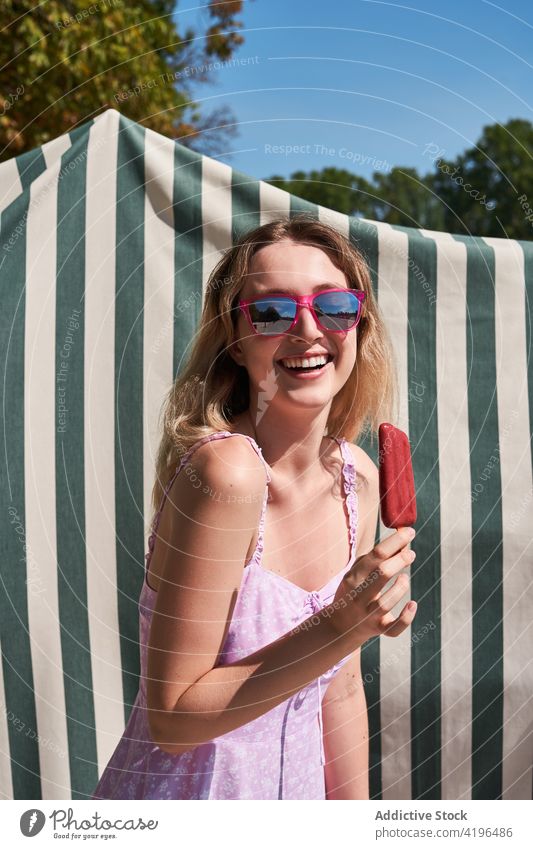 Laughing teen woman eating ice cream in sunny day teenage popsicle sweet laugh delight joy carefree expressive happy female optimist enjoy summer dress positive