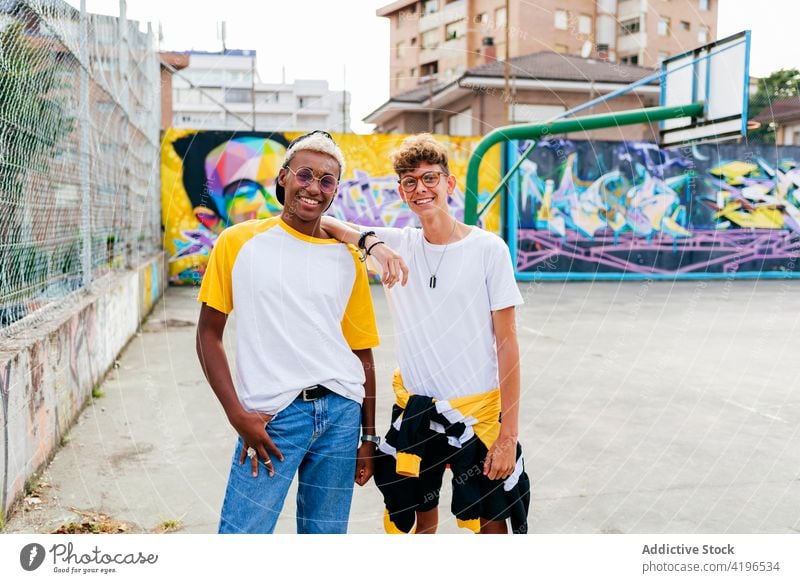 Two teenage boys standing and laughing on the urban basket court autumn black caucasian cheerful city colorful companionship daylight ethnic fellowship friends