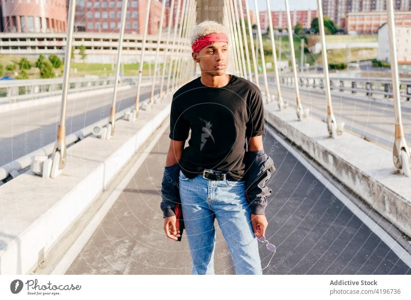 Handsome black boy standing on the street attractive bridge cheerful city colorful confident daylight ethnic handsome headscarf horizontal jacket leisure