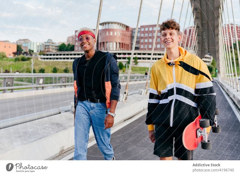 Two handsome teenage boys with skateboard standing on the bridge autumn black caucasian city colorful companionship daylight ethnic fellowship friends
