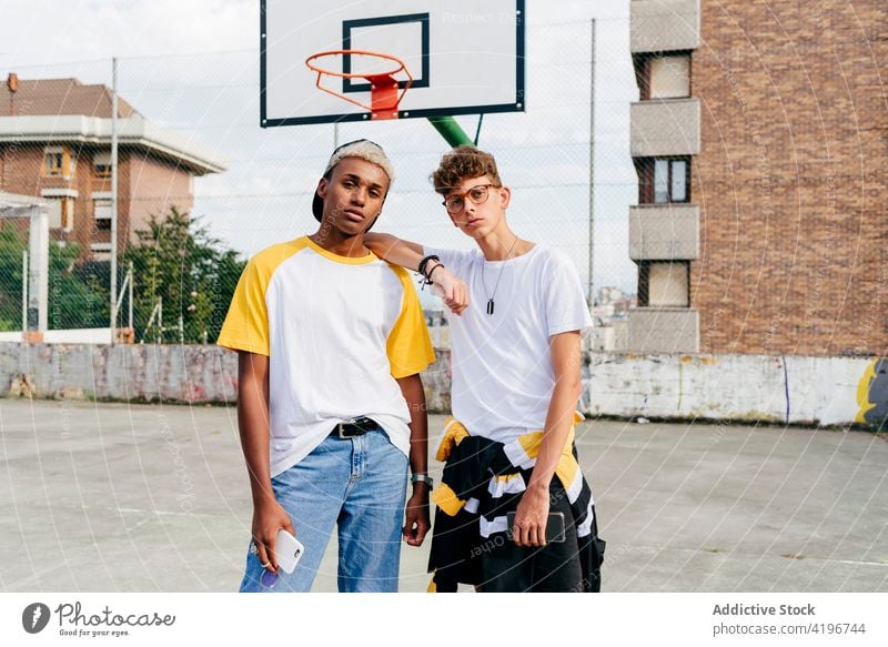 Two teenage boys standing and looking at the camera on the urban basket court autumn black caucasian city colorful companionship daylight ethnic friends