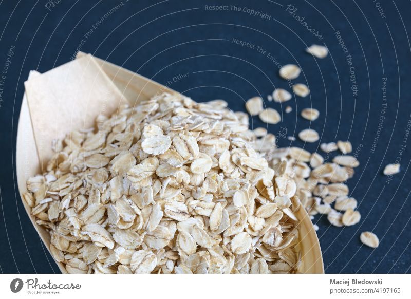 Close up picture of oat flakes in a wooden bowl, selective focus. food porridge oatmeal dry natural raw breakfast fiber healthy cereal ingredient diet organic