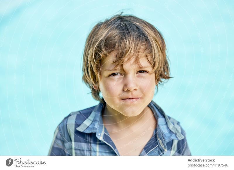 Child scowling and looking at camera in sunlight child frown funny cute portrait mood grimace sweet playful curious stubborn annoyed offend human face kid boy