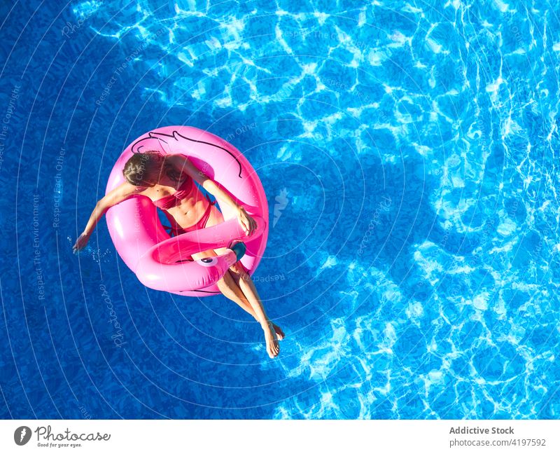 Happy woman floating in swimming pool summer happy inflatable cheerful enjoy vacation relax holiday water ring pink resort recreation rest lifestyle smile chill