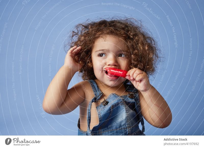 Little girl doing tantrum while holding sweet fruit ice cream kid tired popsicle unwell upset stress curly hair cute unhappy childhood studio shot treat sad cry